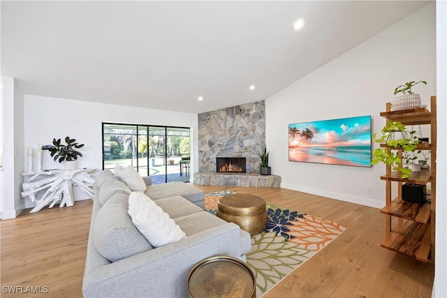 living room featuring vaulted ceiling, a fireplace, and light hardwood / wood-style flooring