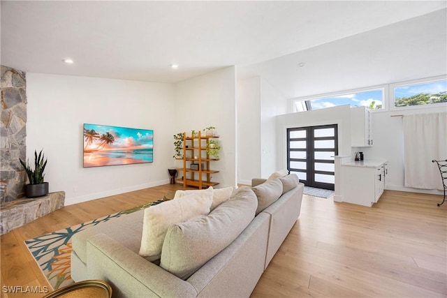 living room with high vaulted ceiling, light hardwood / wood-style floors, and french doors