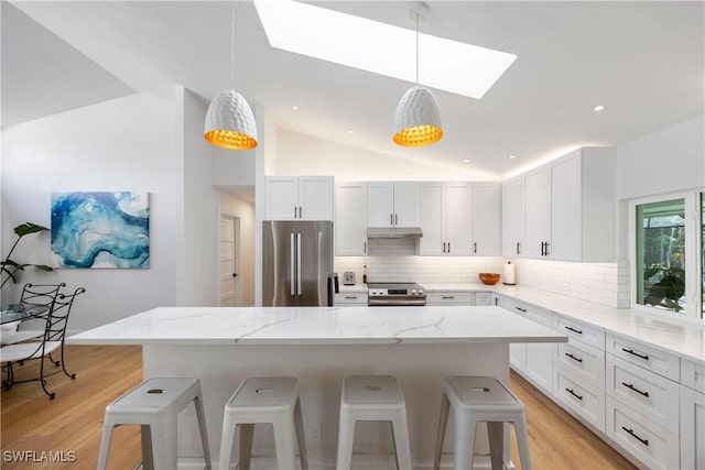 kitchen featuring stainless steel appliances, white cabinetry, a kitchen island, and a breakfast bar