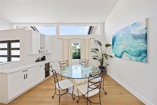 dining room featuring bar area, beverage cooler, and light hardwood / wood-style flooring