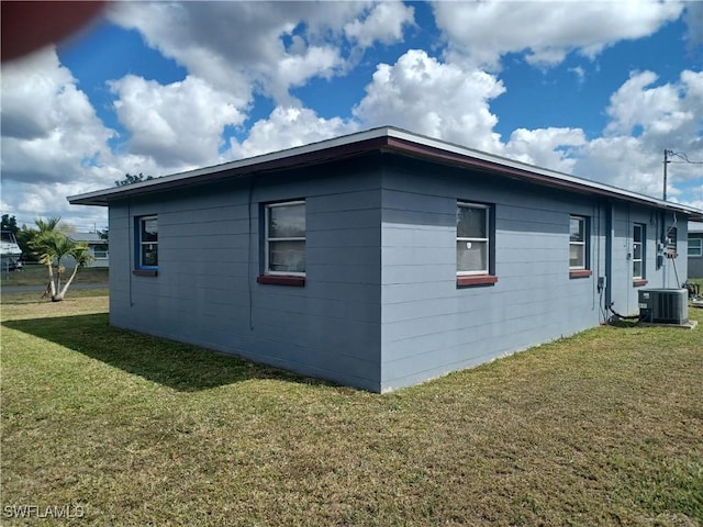 view of side of home featuring a yard and central AC