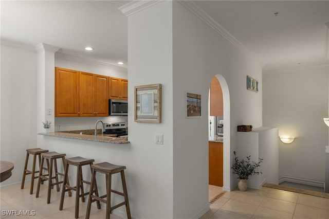 kitchen with light tile patterned flooring, appliances with stainless steel finishes, kitchen peninsula, crown molding, and light stone countertops