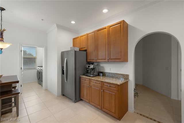 kitchen with pendant lighting, washer / clothes dryer, stainless steel fridge, ornamental molding, and light stone countertops