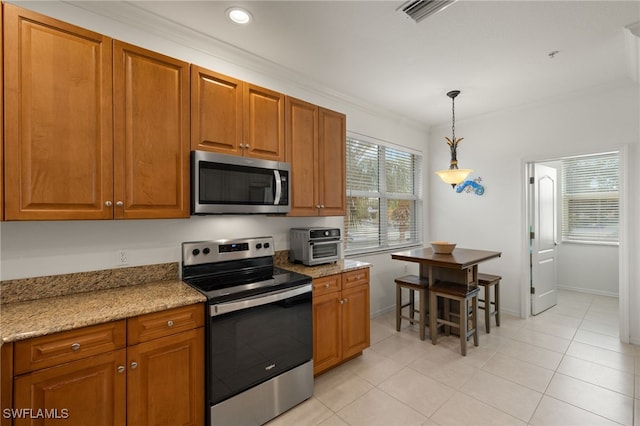 kitchen featuring light tile patterned flooring, ornamental molding, pendant lighting, stainless steel appliances, and light stone countertops