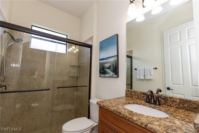 bathroom with vanity, a shower with shower door, and toilet