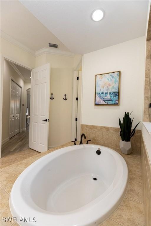 bathroom with crown molding, a relaxing tiled tub, and tile patterned floors