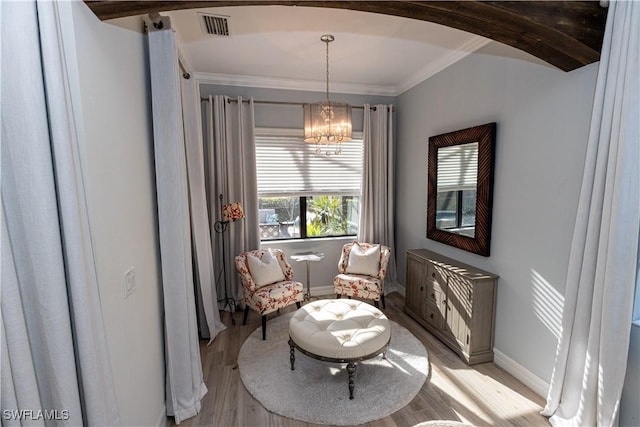 living area with ornamental molding, a chandelier, and light hardwood / wood-style flooring