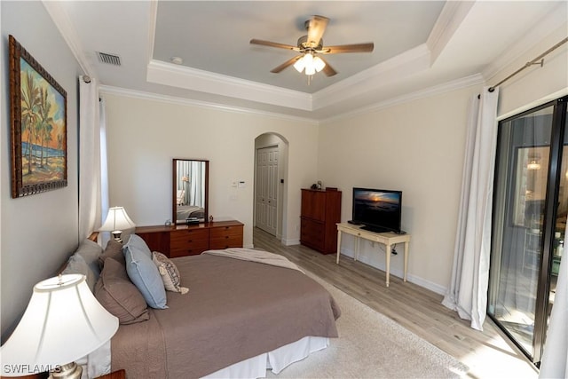 bedroom featuring ornamental molding, a raised ceiling, and light wood-type flooring