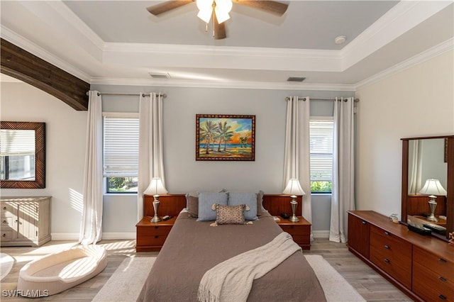 bedroom with multiple windows, crown molding, light hardwood / wood-style flooring, and a raised ceiling