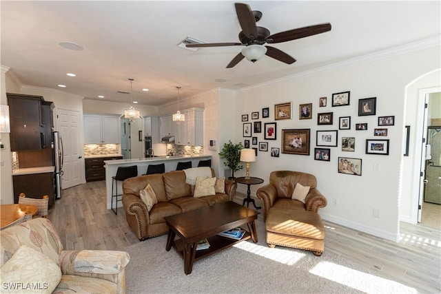 living room featuring light hardwood / wood-style flooring, ornamental molding, and ceiling fan