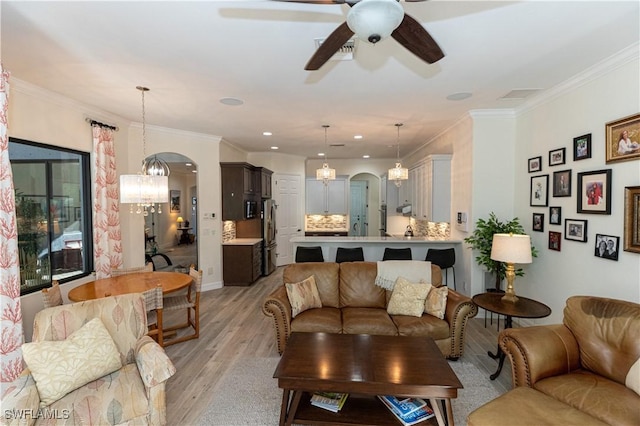 living room with crown molding, ceiling fan with notable chandelier, and light hardwood / wood-style flooring