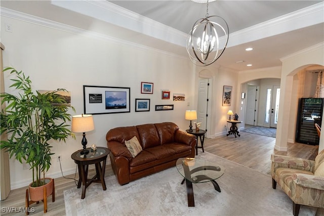 living room with a notable chandelier, crown molding, light hardwood / wood-style floors, and a raised ceiling