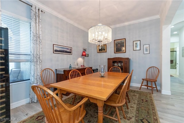 dining space featuring ornamental molding, a chandelier, and light hardwood / wood-style floors