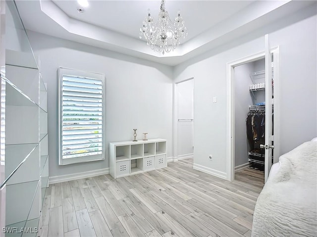 7684 County Rd 78, Fort Denaud, FL 33935 - bedroom with light wood-type flooring, a raised ceiling, a spacious closet, and an inviting chandelier