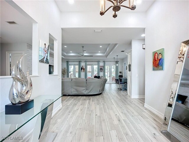 living room with a tray ceiling, recessed lighting, visible vents, light wood-style floors, and baseboards