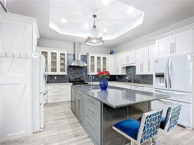 7684 County Rd 78, Fort Denaud, FL 33935 - kitchen featuring wall chimney range hood, glass insert cabinets, white appliances, and a raised ceiling