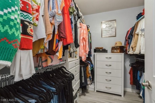 walk in closet with light hardwood / wood-style floors