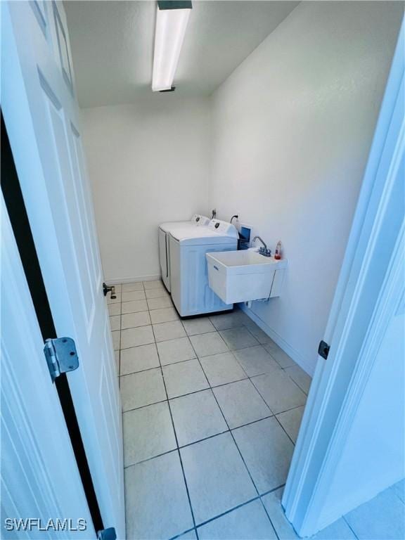 washroom featuring sink, washing machine and dryer, and light tile patterned flooring