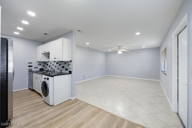 kitchen featuring white cabinets, appliances with stainless steel finishes, washer / dryer, and sink