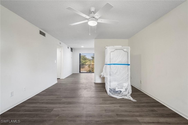 empty room featuring ceiling fan, dark wood-type flooring, and a textured ceiling