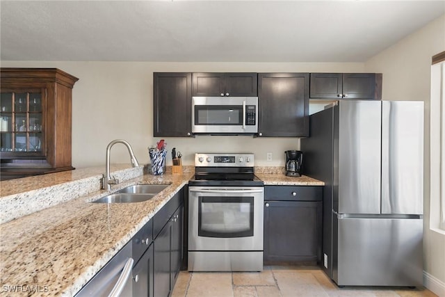 kitchen featuring dark brown cabinetry, sink, light stone counters, kitchen peninsula, and stainless steel appliances