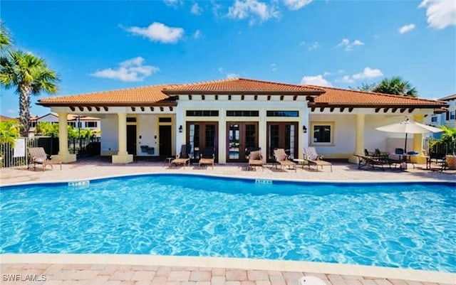 rear view of house featuring a community pool and a patio