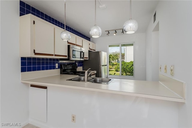 kitchen with sink, appliances with stainless steel finishes, white cabinets, pendant lighting, and backsplash