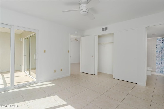 unfurnished bedroom featuring light tile patterned flooring, connected bathroom, ceiling fan, and a closet