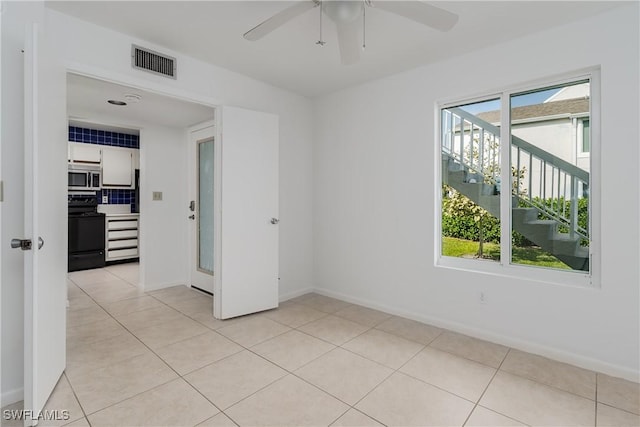 tiled empty room featuring plenty of natural light and ceiling fan