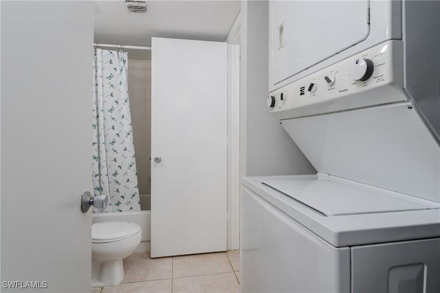 washroom with stacked washer / drying machine and light tile patterned floors