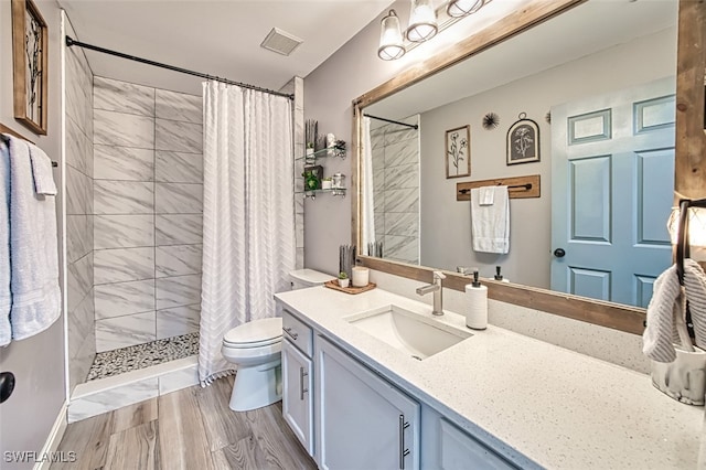 bathroom featuring hardwood / wood-style flooring, vanity, curtained shower, and toilet