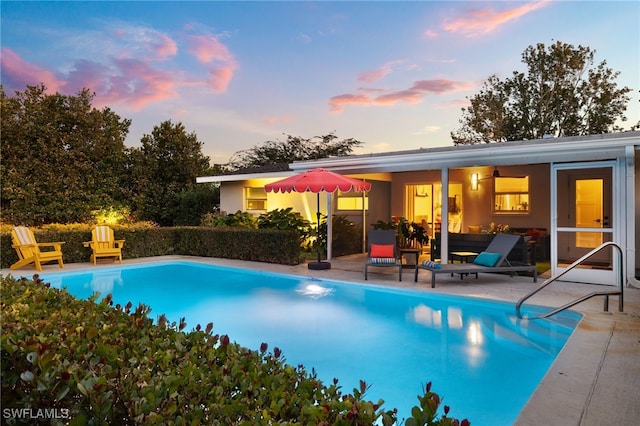 pool at dusk featuring a patio area and an outdoor pool