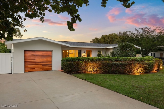 ranch-style house featuring an attached garage, a yard, concrete driveway, and stucco siding