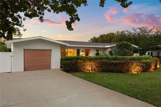 ranch-style house with stucco siding, driveway, fence, a front yard, and a garage