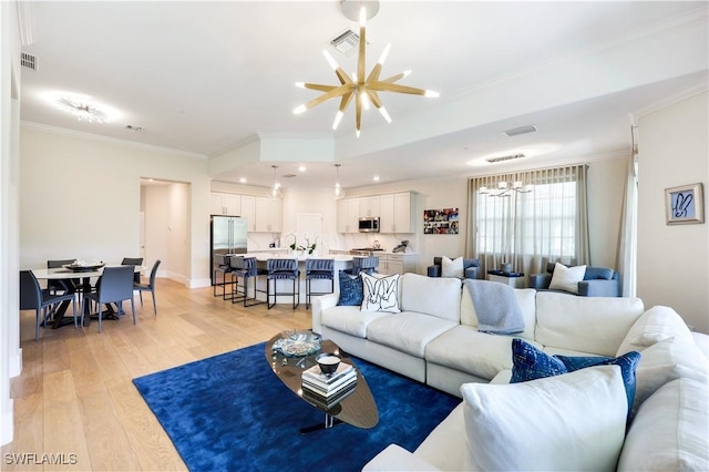 living room with ornamental molding, light wood-type flooring, and a notable chandelier