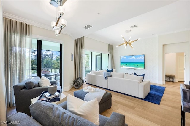 living room featuring a notable chandelier, crown molding, and light wood-type flooring