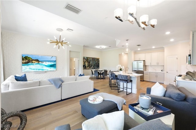 living room featuring ornamental molding, a notable chandelier, and light wood-type flooring