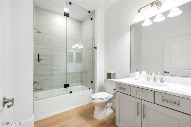 full bathroom featuring toilet, vanity, shower / bath combination with glass door, and hardwood / wood-style flooring