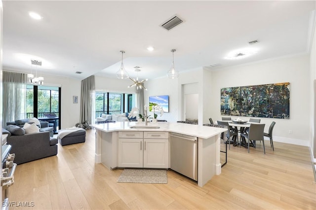 kitchen with an inviting chandelier, decorative light fixtures, stainless steel appliances, and an island with sink