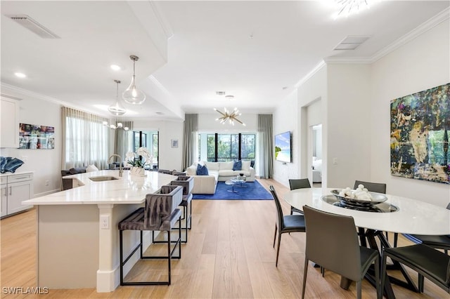 kitchen featuring white cabinetry, sink, a breakfast bar area, a kitchen island with sink, and an inviting chandelier