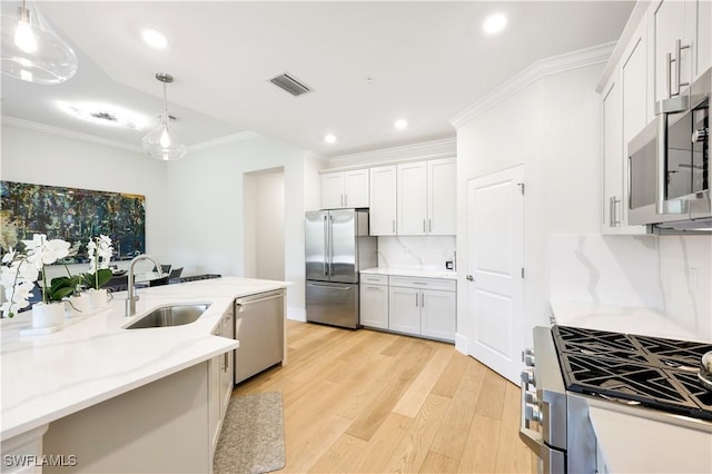 kitchen featuring sink, hanging light fixtures, white cabinets, and appliances with stainless steel finishes