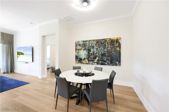 dining space with crown molding and light hardwood / wood-style flooring