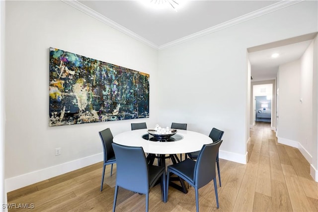 dining area with crown molding and light hardwood / wood-style floors