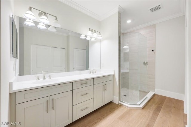 bathroom featuring a shower with door, ornamental molding, wood-type flooring, and vanity