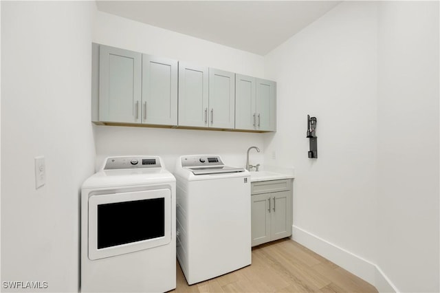 washroom with sink, light hardwood / wood-style flooring, cabinets, and washing machine and clothes dryer