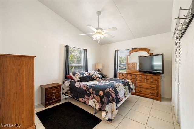 bedroom featuring ceiling fan, lofted ceiling, multiple windows, and light tile patterned floors