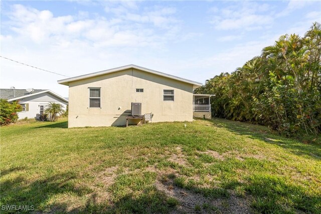 back of house with a sunroom, central AC, and a lawn