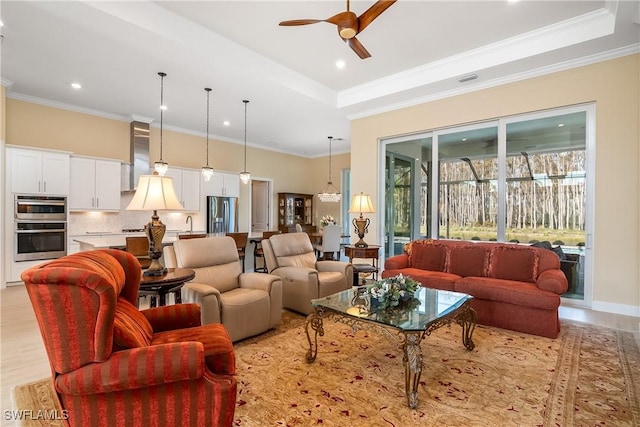 living room with crown molding, a tray ceiling, and light hardwood / wood-style floors