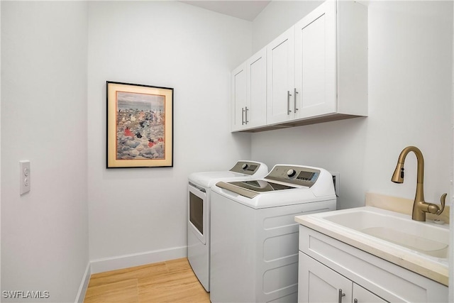 laundry area featuring light hardwood / wood-style floors, cabinets, separate washer and dryer, and sink