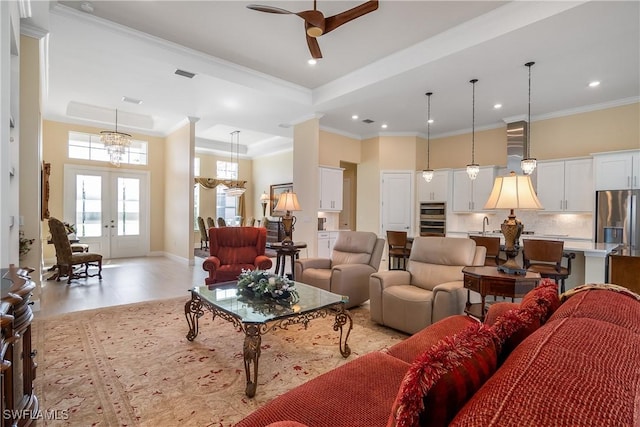 living room featuring a high ceiling, ornamental molding, ceiling fan, a tray ceiling, and french doors